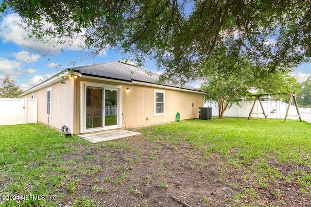 rear view of property with a lawn and cooling unit