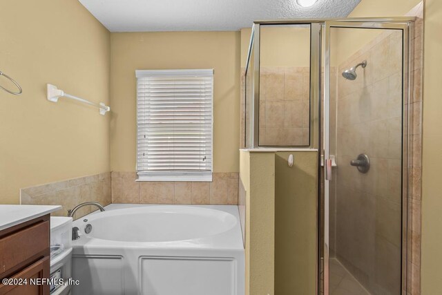 bathroom with separate shower and tub, a textured ceiling, and vanity