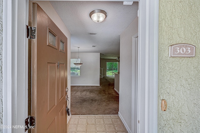 hall with a textured ceiling and light carpet