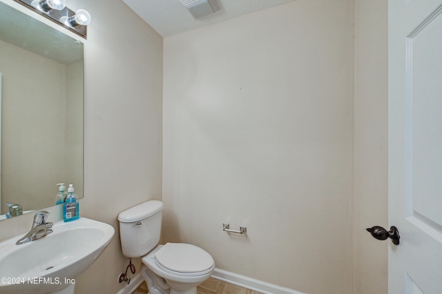 bathroom with sink, toilet, and a textured ceiling