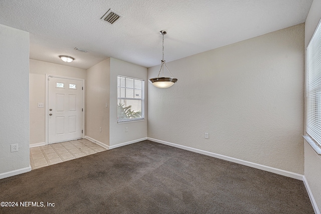 entrance foyer with a textured ceiling and light carpet