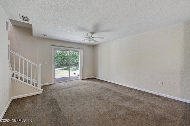 spare room featuring ceiling fan, dark colored carpet, and a textured ceiling