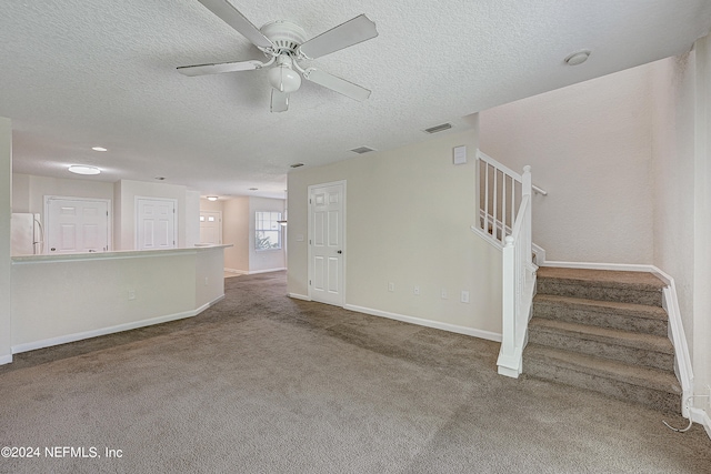 unfurnished living room with ceiling fan, carpet flooring, and a textured ceiling