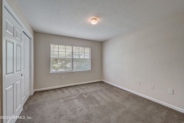 unfurnished bedroom with a textured ceiling, a closet, and carpet