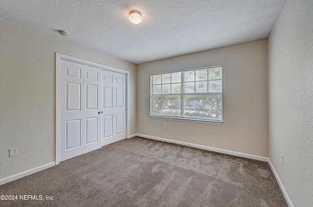 unfurnished bedroom featuring carpet floors, a closet, and a textured ceiling