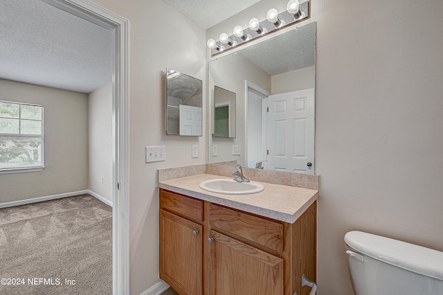 bathroom featuring a textured ceiling, vanity, and toilet