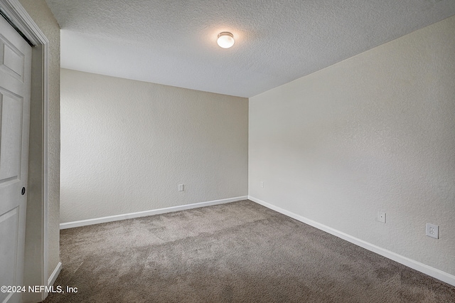 unfurnished bedroom with a textured ceiling, a closet, and carpet