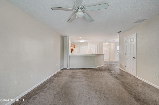 unfurnished living room with ceiling fan, light carpet, and a textured ceiling