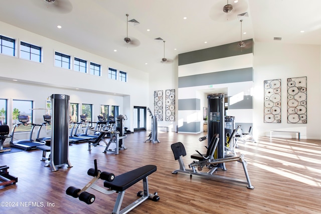 gym with hardwood / wood-style flooring, high vaulted ceiling, and ceiling fan