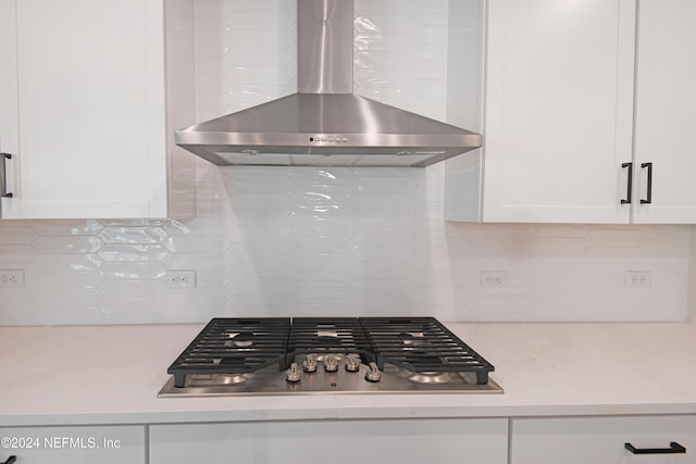 kitchen featuring backsplash, white cabinetry, wall chimney range hood, and stainless steel gas stovetop