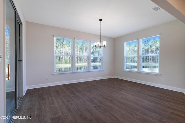 unfurnished dining area featuring a chandelier and dark hardwood / wood-style flooring