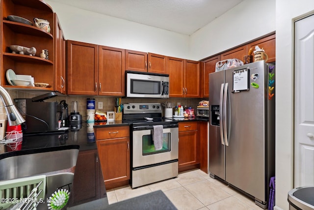 kitchen with appliances with stainless steel finishes, tasteful backsplash, sink, light tile patterned floors, and a textured ceiling