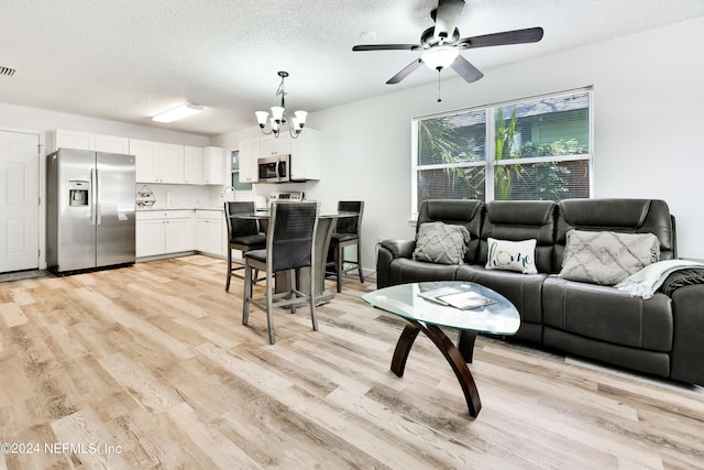 living room featuring light wood-type flooring, a textured ceiling, and ceiling fan with notable chandelier