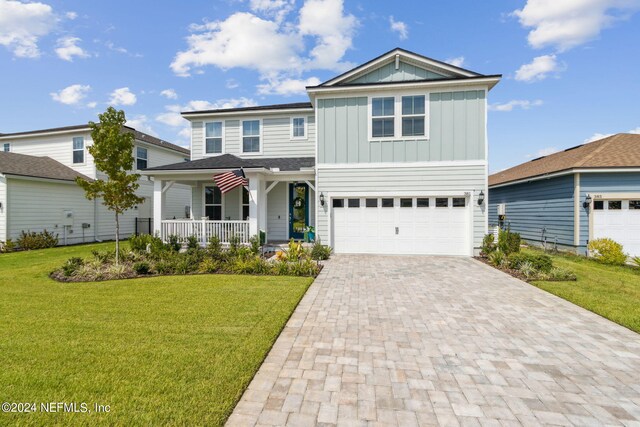 view of front of property featuring a garage, a porch, and a front lawn