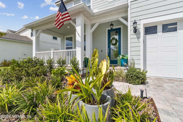 doorway to property featuring a garage and a porch