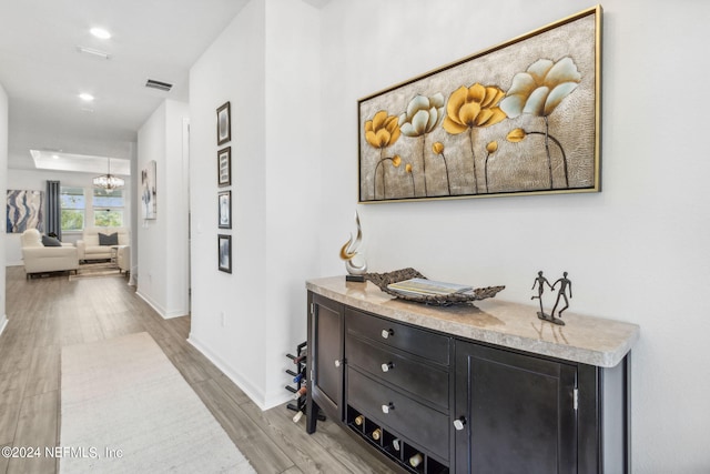 hallway featuring a chandelier and light hardwood / wood-style flooring