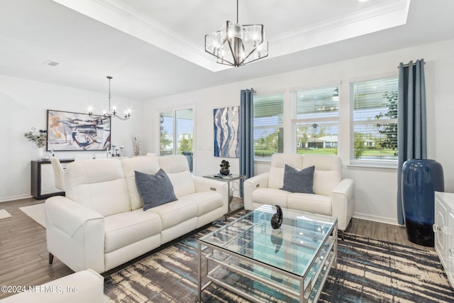 living room with a tray ceiling, an inviting chandelier, dark hardwood / wood-style flooring, and crown molding