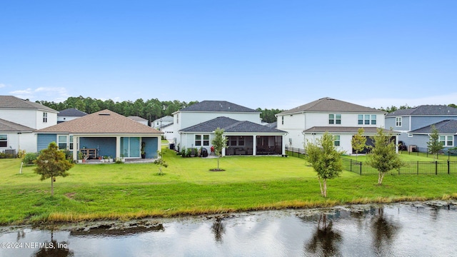 rear view of house featuring a yard, a water view, a patio area, and a sunroom