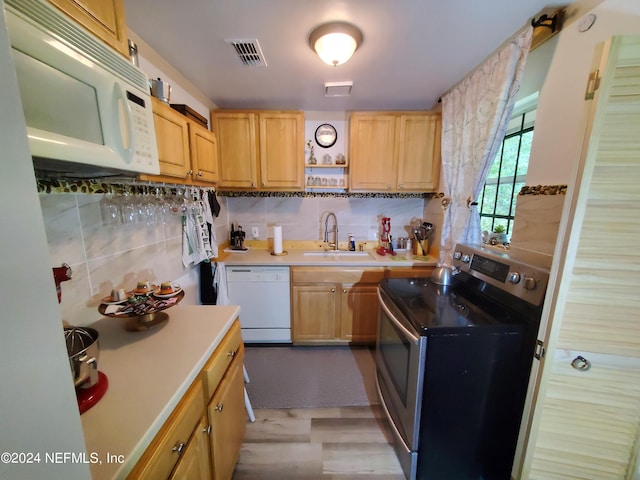 kitchen featuring sink, light hardwood / wood-style flooring, backsplash, and white appliances