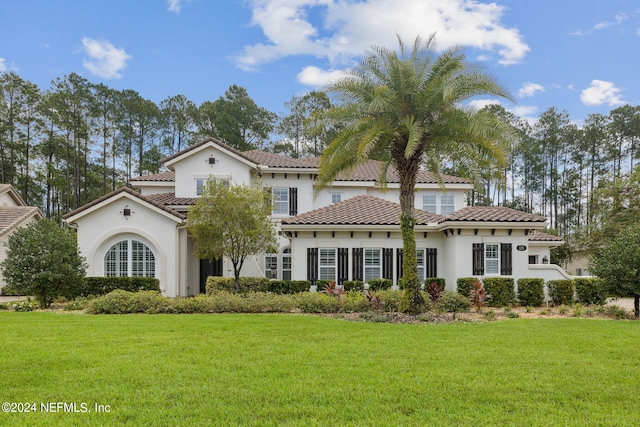 mediterranean / spanish home with stucco siding, a front lawn, and a tile roof