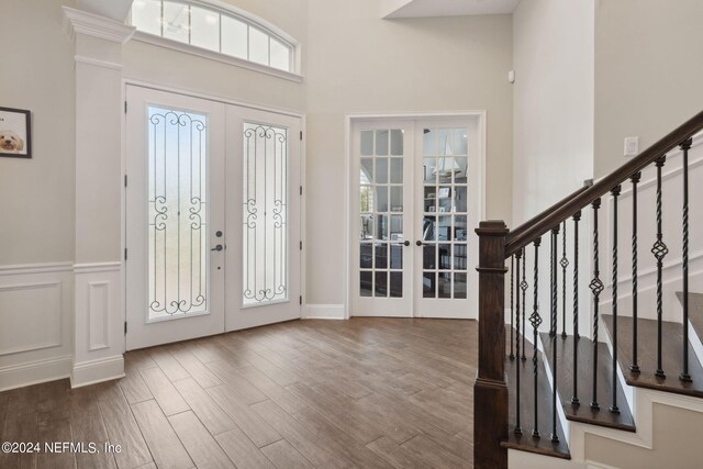 entryway with a towering ceiling, french doors, and wood-type flooring