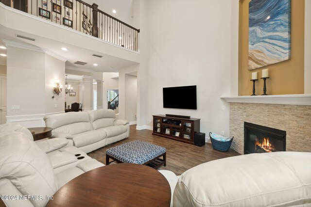 living room featuring ornate columns, a towering ceiling, dark hardwood / wood-style flooring, and a fireplace