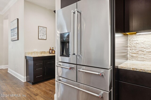 kitchen featuring dark brown cabinetry, wood-type flooring, light stone countertops, and high end fridge