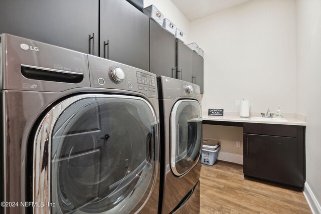 clothes washing area with washing machine and dryer, cabinets, sink, and light hardwood / wood-style floors