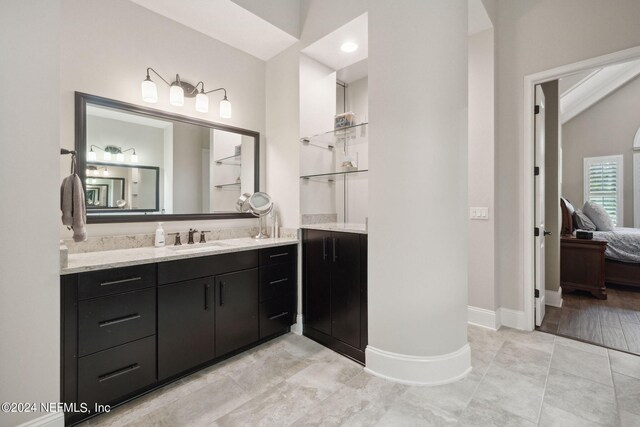 bathroom with lofted ceiling, built in shelves, tile patterned flooring, and vanity