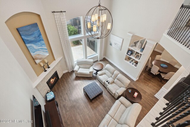 living room with dark wood-type flooring, an inviting chandelier, and a towering ceiling