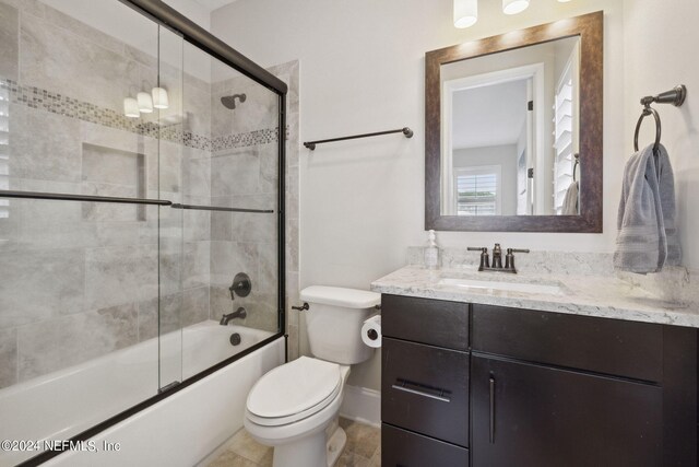 full bathroom featuring tile patterned flooring, toilet, combined bath / shower with glass door, and vanity