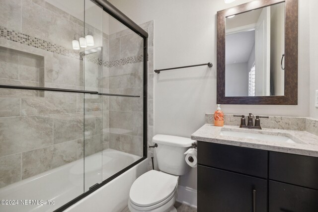 full bathroom featuring vanity, toilet, and bath / shower combo with glass door