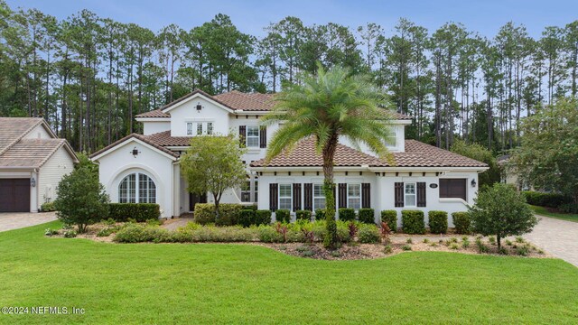 mediterranean / spanish house featuring a front lawn and a garage