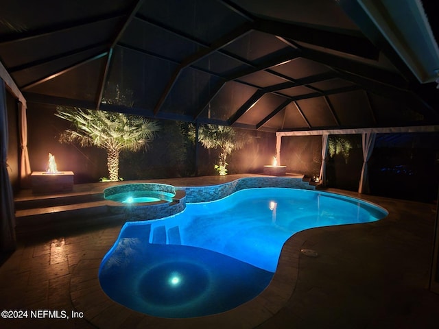 view of pool featuring a lanai, a pool with connected hot tub, and a patio