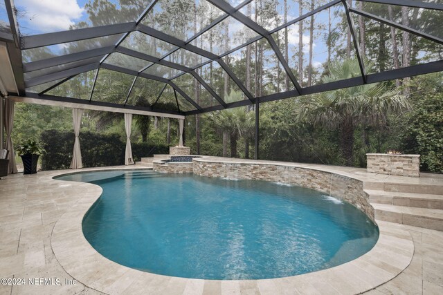 view of swimming pool with pool water feature, a lanai, an in ground hot tub, and a patio area