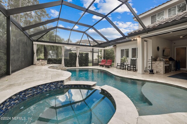 view of swimming pool with a lanai, an in ground hot tub, an outdoor kitchen, a bar, and a patio