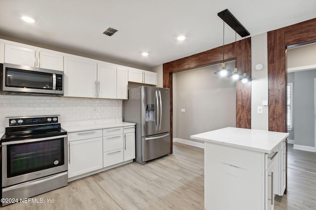 kitchen featuring light hardwood / wood-style floors, white cabinetry, a kitchen island, stainless steel appliances, and decorative light fixtures