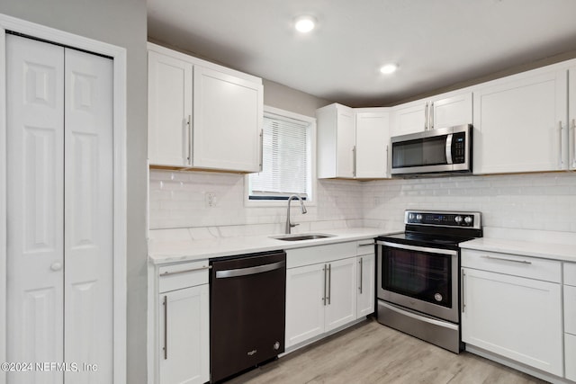 kitchen featuring a sink, white cabinets, appliances with stainless steel finishes, and light wood-style flooring