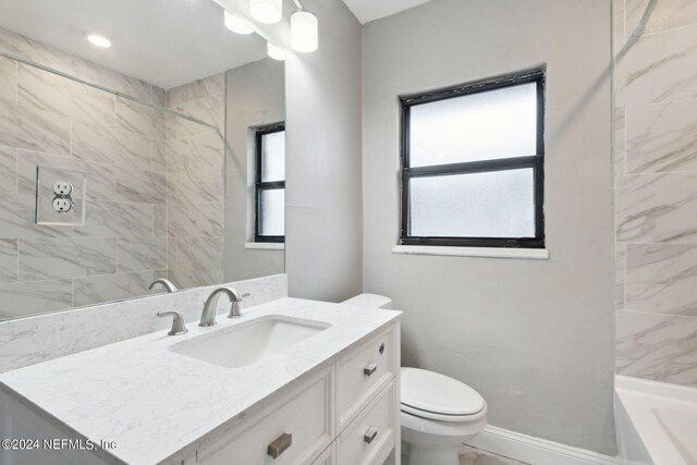 full bathroom with tiled shower / bath, vanity, and toilet