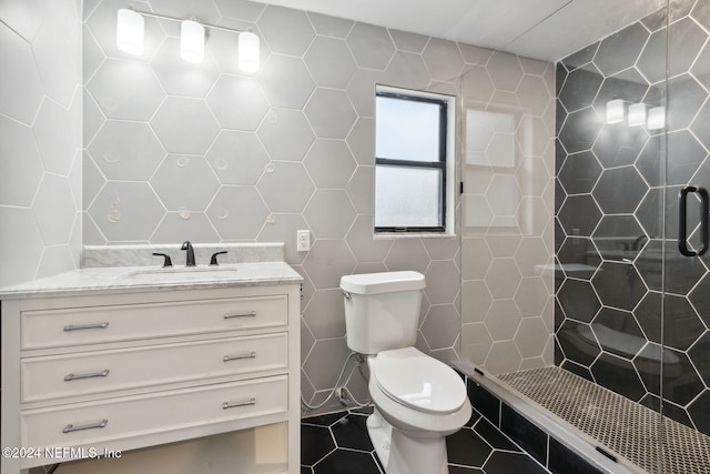 bathroom featuring tile walls, a shower with shower door, vanity, tile patterned flooring, and toilet