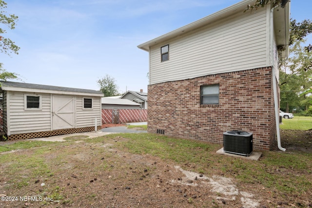 view of side of property featuring fence, an outbuilding, brick siding, and a storage unit