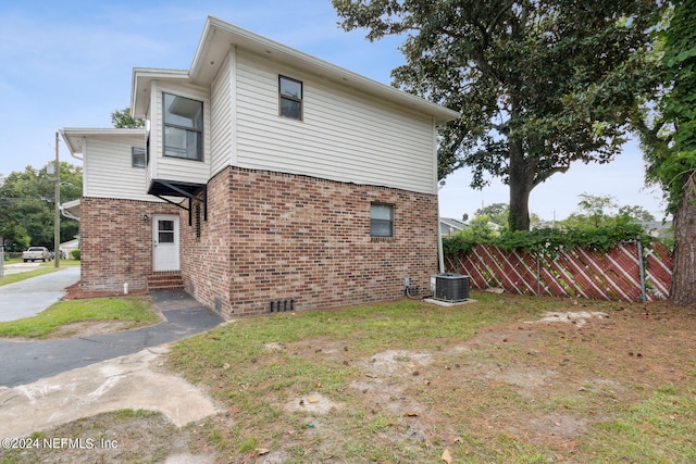 view of home's exterior with fence, brick siding, central AC unit, and entry steps