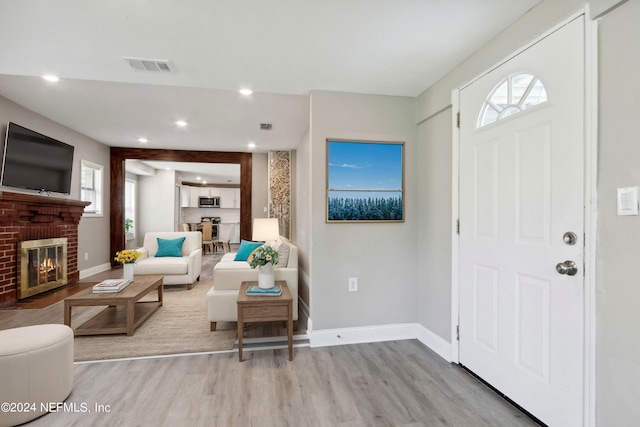 foyer with baseboards, visible vents, a fireplace, and light wood-type flooring