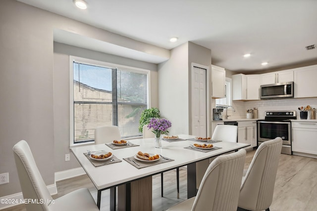 dining space with light hardwood / wood-style floors and sink