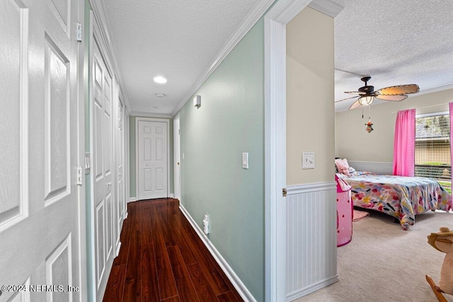 hallway with a textured ceiling, dark hardwood / wood-style floors, and ornamental molding