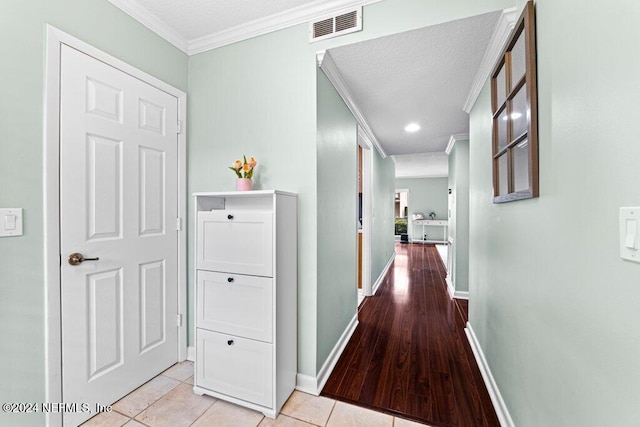 hall with light tile patterned floors, a textured ceiling, and ornamental molding