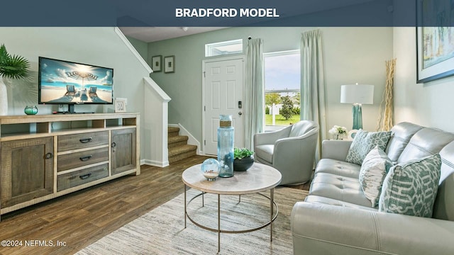 living area with dark wood-style floors, stairs, and baseboards