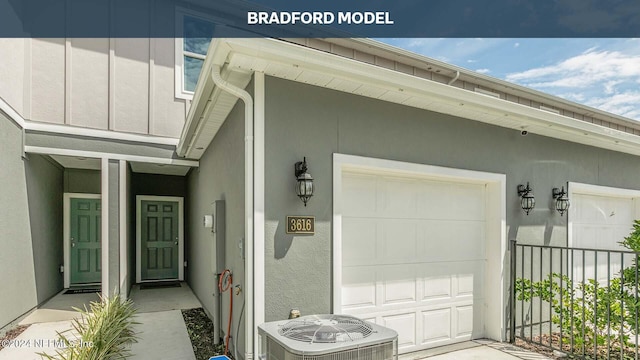 view of exterior entry featuring central air condition unit, a garage, board and batten siding, and stucco siding