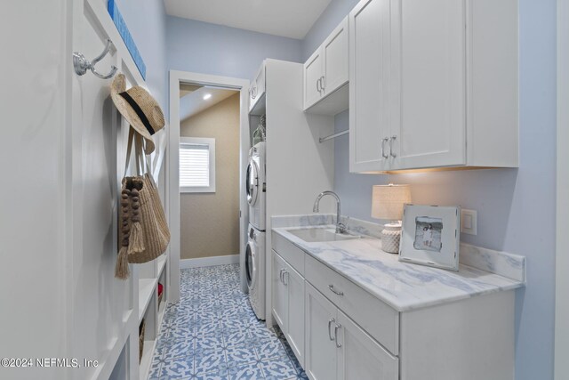 interior space with stacked washer / drying machine, white cabinetry, sink, and light stone countertops