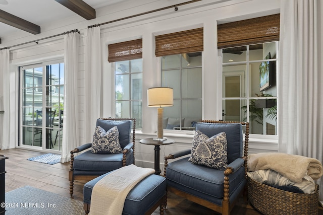 living area with wood-type flooring, plenty of natural light, and beam ceiling